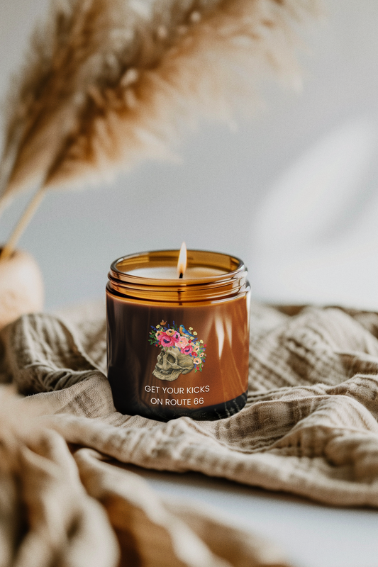 Floral Skull Route 66 amber jar candle burning on soft fabric, cozy rustic home décor scene