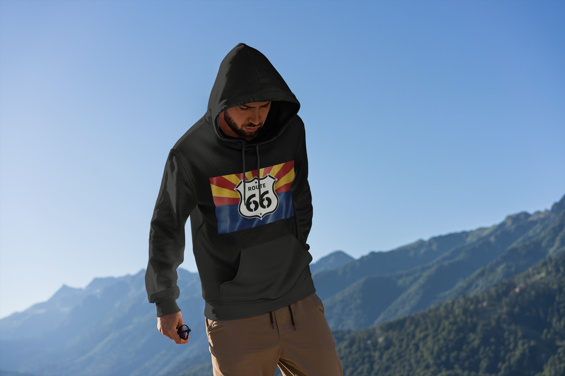 Man wearing a black Route 66 Arizona Flag hoodie outdoors in the mountains, perfect for travel and road trips.