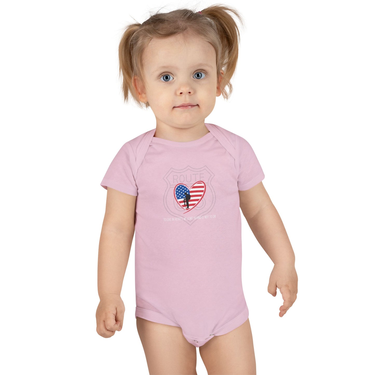 Toddler standing and smiling while wearing a pink Route 66 baby onesie with American flag heart and remembrance quote, perfect for Memorial Day or Independence Day.