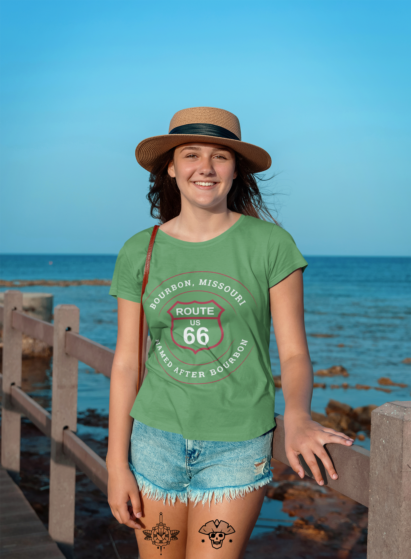 Female model wearing a straw hat with a black stripe and a leaf retro Route 66 unisex jersey tee with a Bourbon, MO: "Named After Bourbon" design