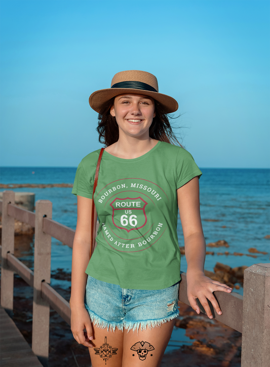 Female model wearing a straw hat with a black stripe and a leaf retro Route 66 unisex jersey tee with a Bourbon, MO: "Named After Bourbon" design
