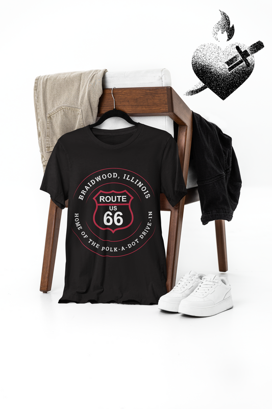 A black heather retro Route 66 unisex jersey tee with a Godley, IL: "Coal City" design hangs behind a chair