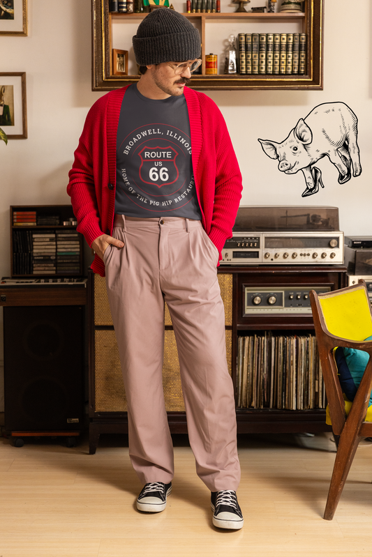 Female model wearing a dark grey heather retro Route 66 unisex jersey tee with a Broadwell, IL: "Home of the Pig Hip Restaurant" design