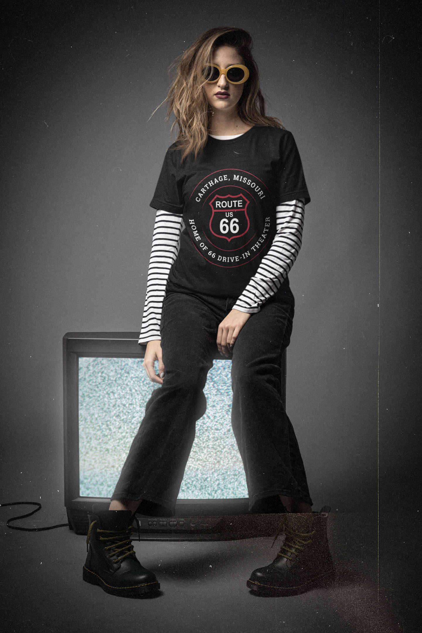 Female model wearing black heather retro Route 66 unisex jersey tee with Carthage, MO "Home of 66 Drive-in Theater" design