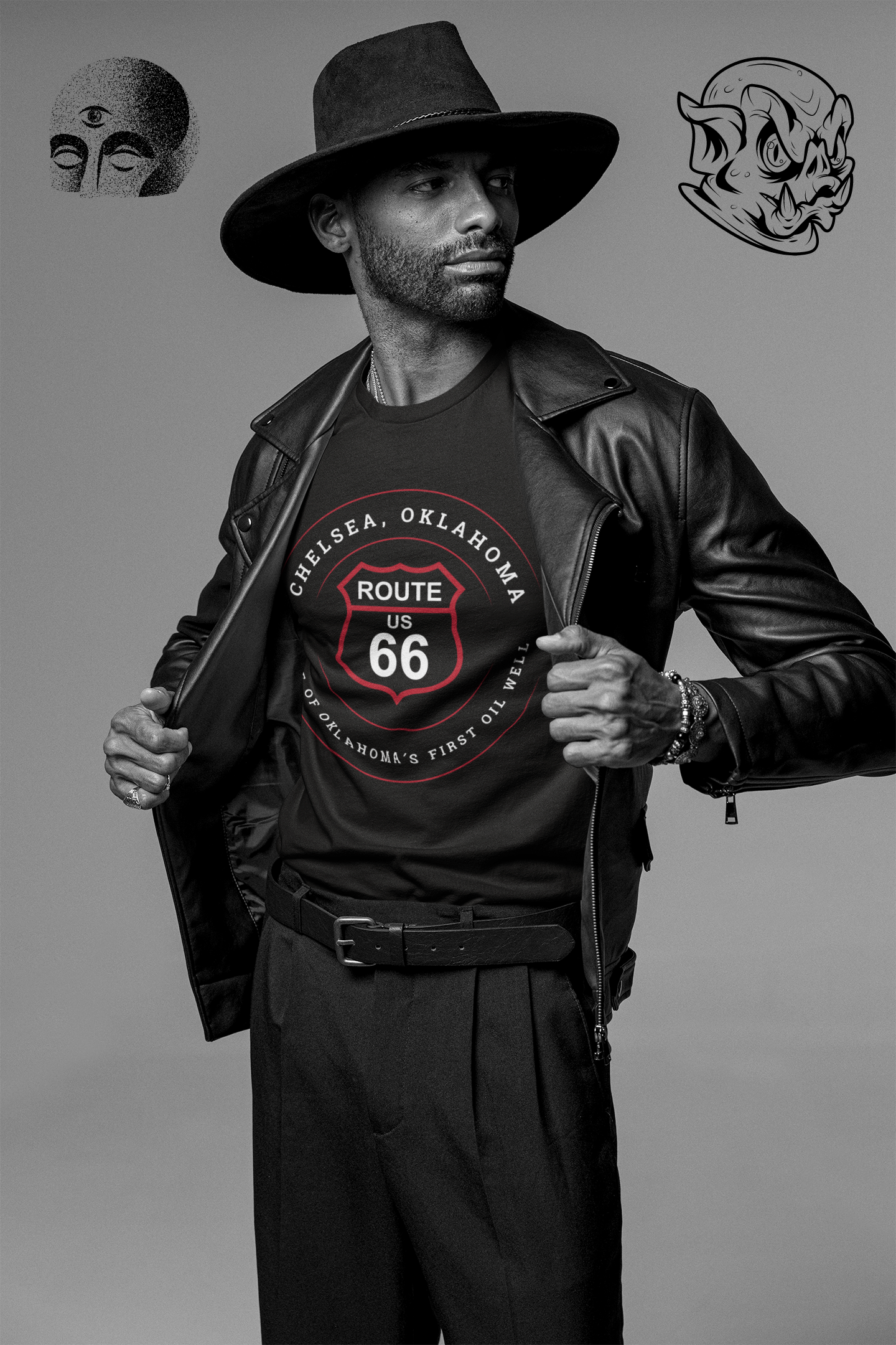 Black retro Route 66 unisex jersey tee with Chelsea, OK 'Home of Oklahoma’s First Oil Well' design, worn by a man in a wide-brim hat and leather jacket posing against a gray studio background with strange graphics