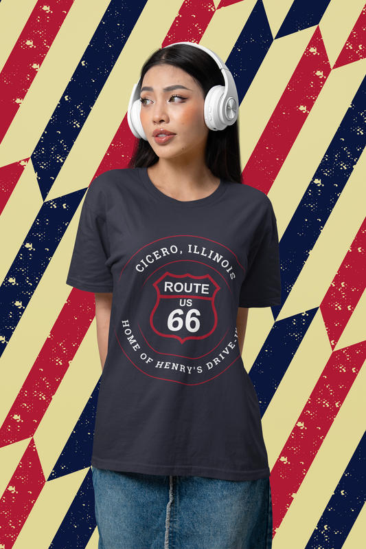 Female model wearing a heather true royal retro Route 66 unisex jersey tee with a Cicero, IL:: "Home of Henry's Drive-In" design. The background is an Americana red, white and blue pattern