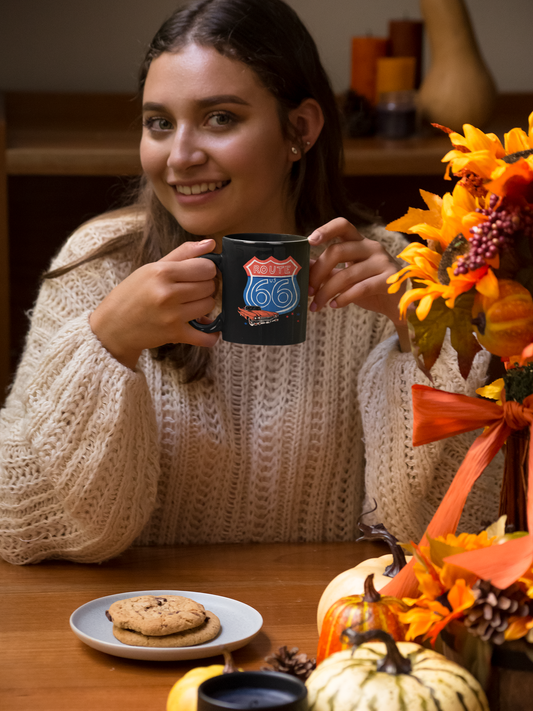 Smiling woman enjoying coffee from a Route 66 Corvette latte mug at a cozy autumn table with pumpkins and cookies