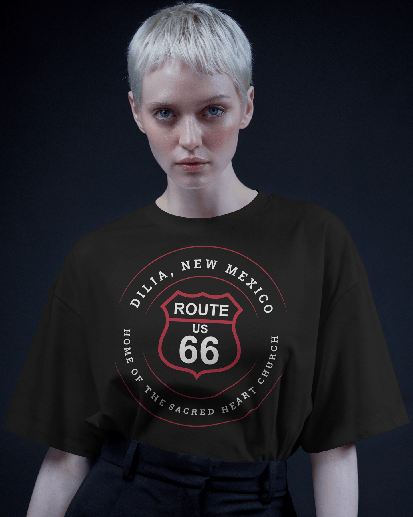 Female model wearing black heather retro Route 66 unisex jersey tee with Dilia, NM: A Home of the Sacred Heart Church
