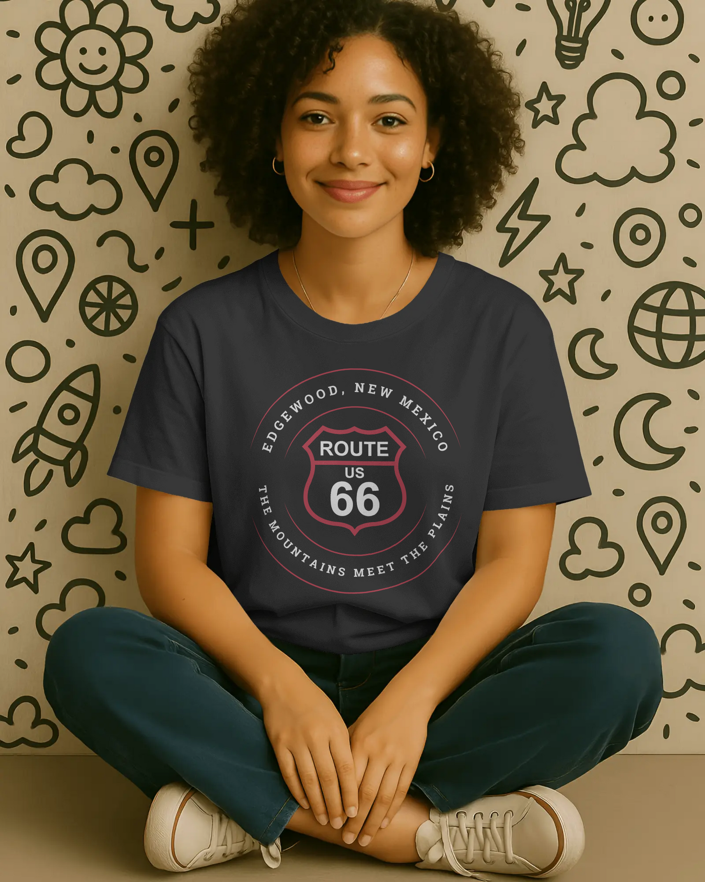 Female model wearing a black retro Route 66 unisex jersey tee with a Edgewood, NM: "The Mountains Meet The Plains" design