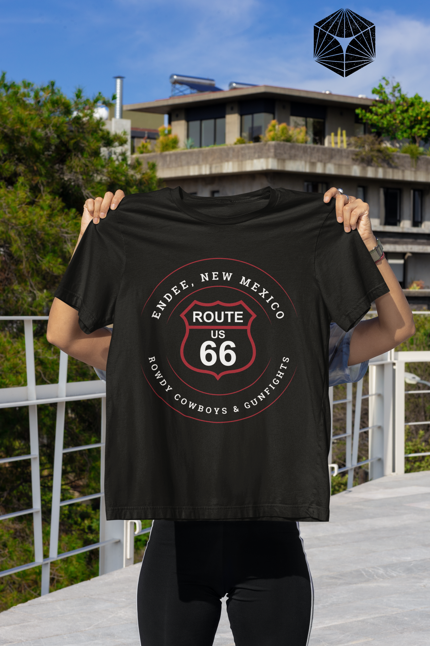 Female model holding a black retro Route 66 unisex jersey tee with Endee, NM: "Rowdy Cowboys & Gunfights" design