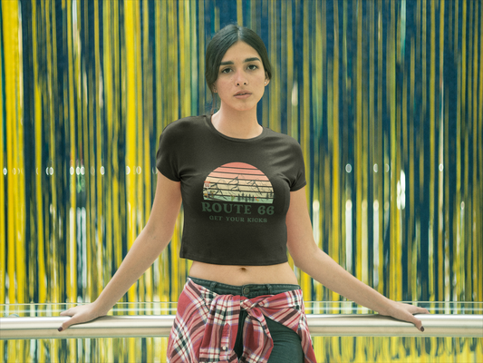 Woman wearing a black Route 66 "Get Your Kicks" baby tee with retro sunset mountain design.