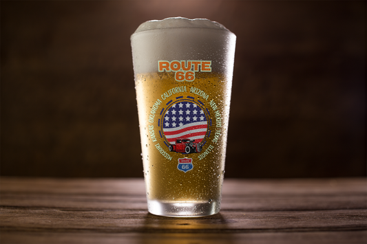 Close-up of Route 66 pint glass filled with beer, featuring a classic red truck and American flag design with all eight Route 66 states listed around the artwork
