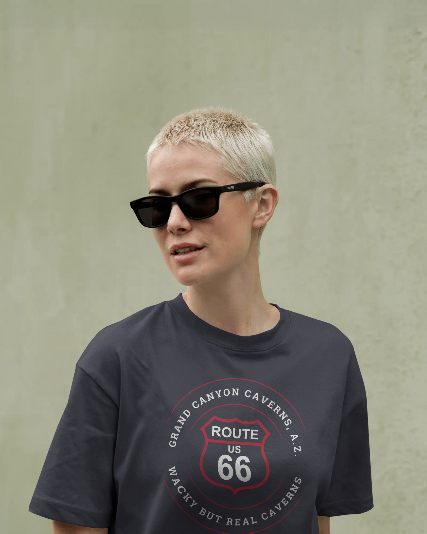 Female model wearing black sunglasses and a vintage black retro Route 66 unisex jersey tee with Grand Canyon Caverns, AZ: "Wacky But Real" design