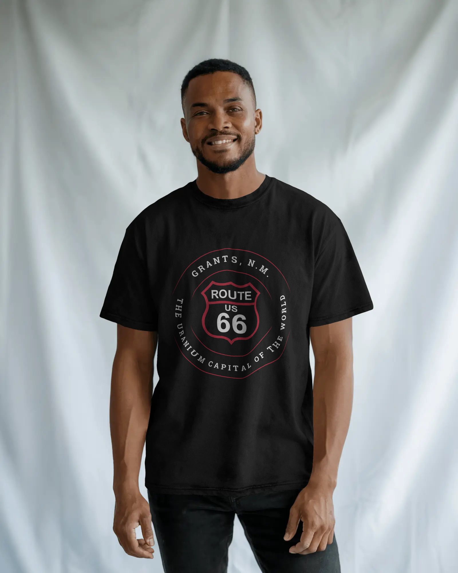 Male model wearing black retro Route 66 unisex jersey tee with Grants, NM: "Uranium Capital of the World" design