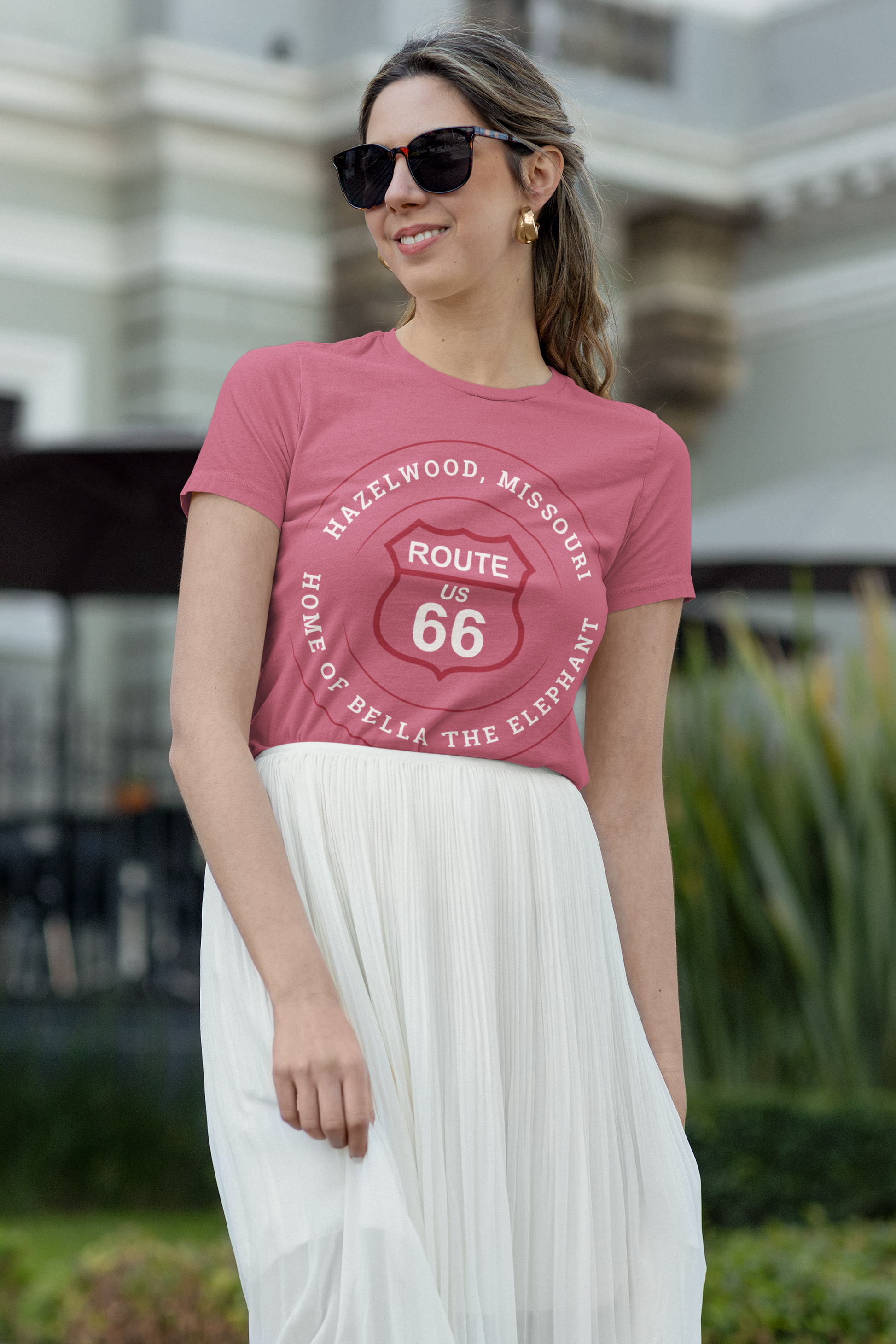 Female model wearing a heather raspberry retro Route 66 unisex jersey tee with a Hazelwood, MO: "Home of Bella the Elephant" design