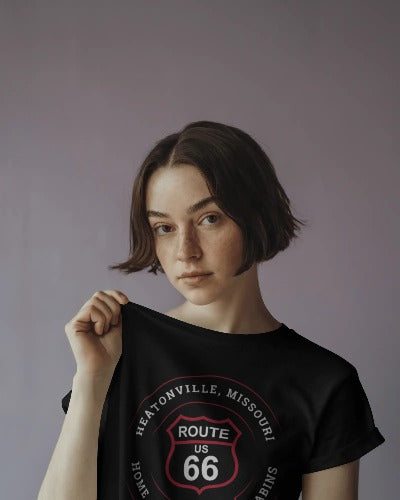 Female model wearing black retro Route 66 unisex jersey tee with Heatonville, MO "Home of Castlerock Cabins" design