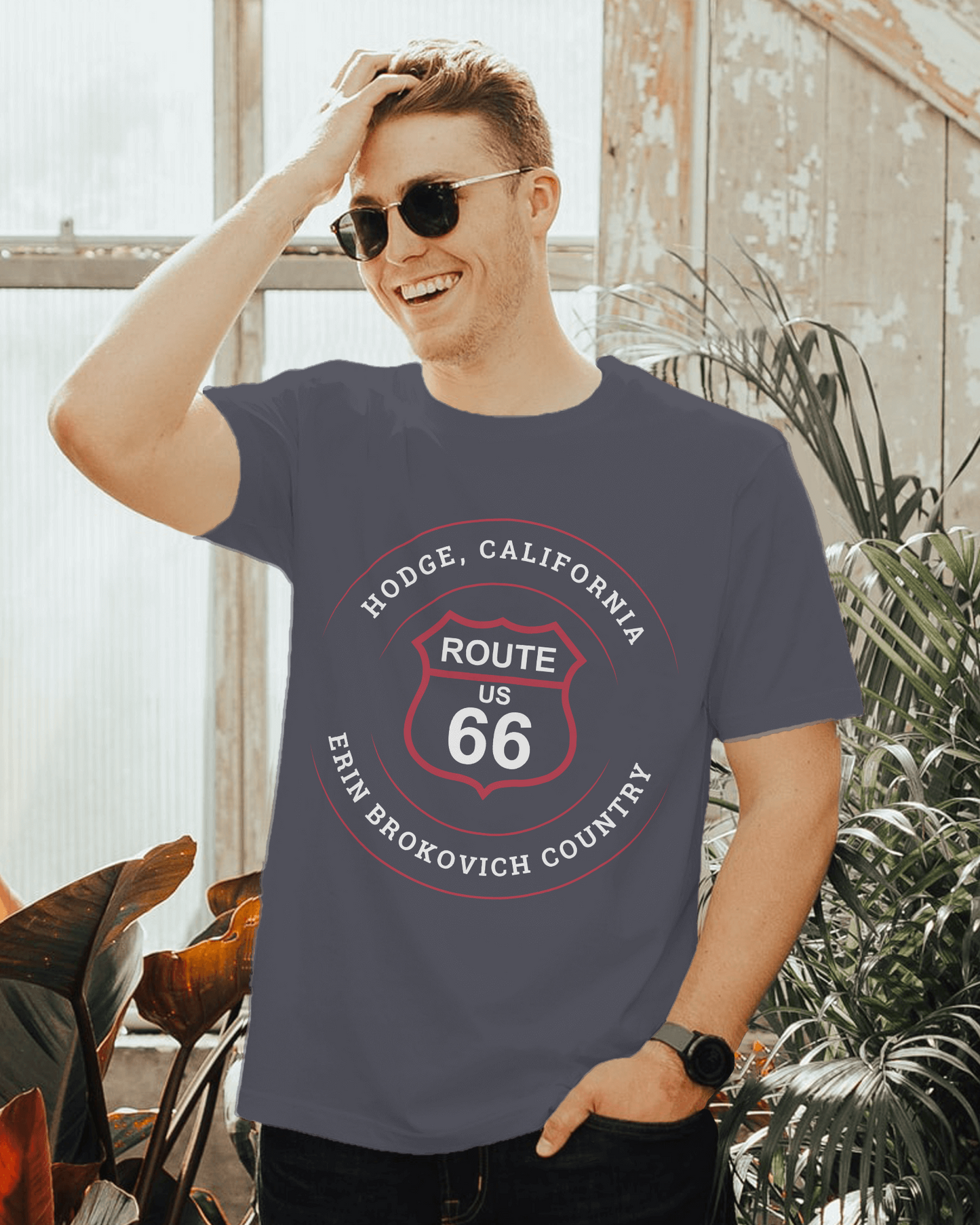 Male model wearing a heather navy retro Route 66 unisex jersey tee with a Hodge, CA: "Erin Brockovich Country" design