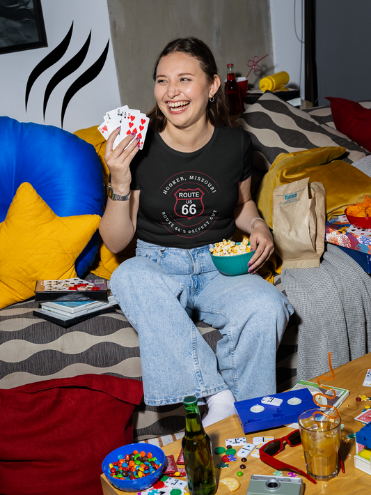 Female model wearing a black retro Route 66 unisex jersey tee with a Hooker, MO: "Route 66's Deepest Cut" design