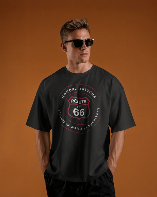 Male model wearing sunglasses and a vintage black retro Route 66 unisex jersey tee with Houck, AZ: "Village in Navajo Territory" design
