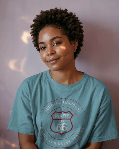 Female model wearing a turquoise retro Route 66 unisex jersey tee with a Jerome, MO: "Named for Saint John" design