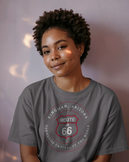 Female model wearing dark grey heather retro Route 66 unisex jersey tee with Kingman, AZ: "Turquoise Capital of the World" design