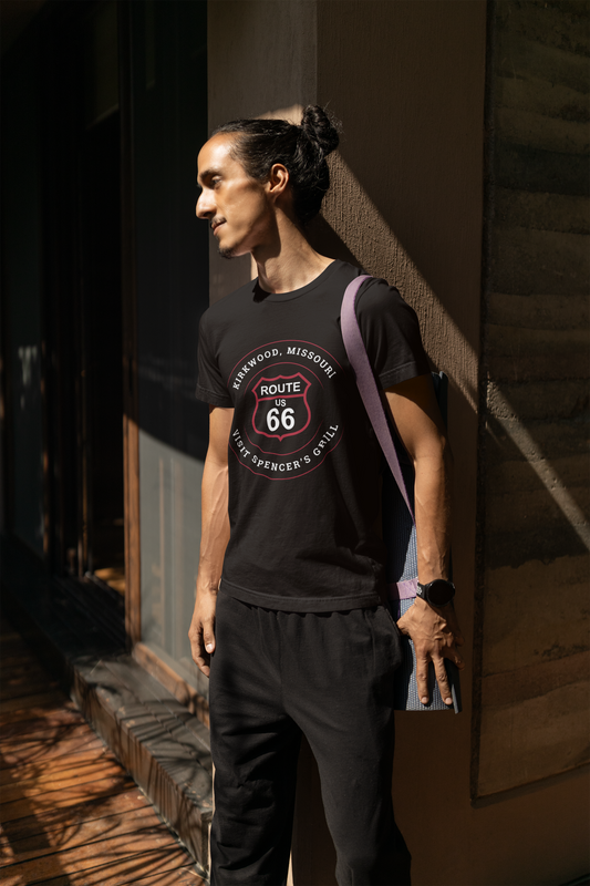 Male model wearing a black retro Route 66 unisex jersey tee with a Kirkwood, MO: "Visit Spencer's Grill" design