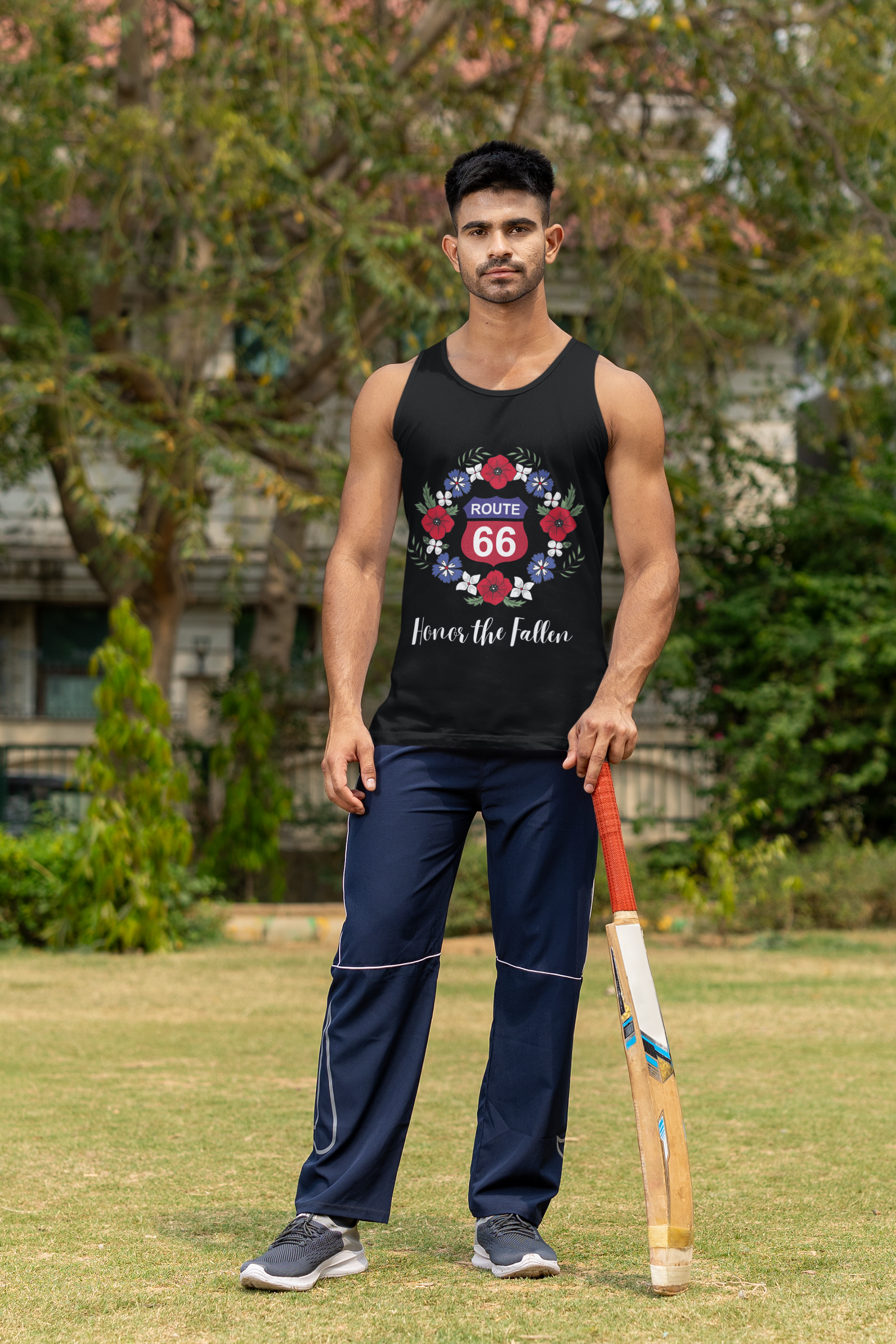 Athletic man wearing a black Route 66 "Honor the Fallen" tank top standing on grass with a cricket bat