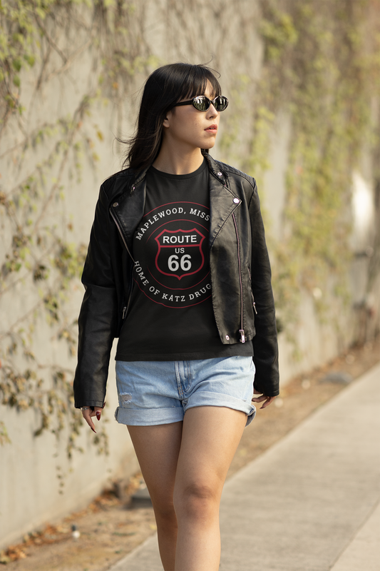 Female model wearing a black heather retro Route 66 unisex jersey tee with a Maplewood, MO: "Home of Katz Drugstore" design