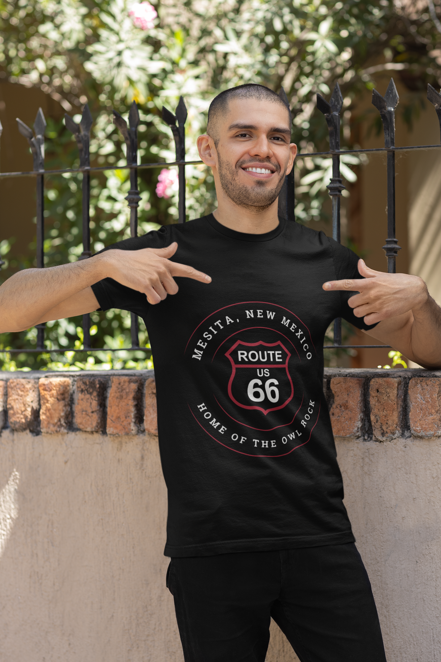 Male model wearing a black retro Route 66 unisex jersey tee with a Mesita, NM: "Home of the Owl Rock" design
