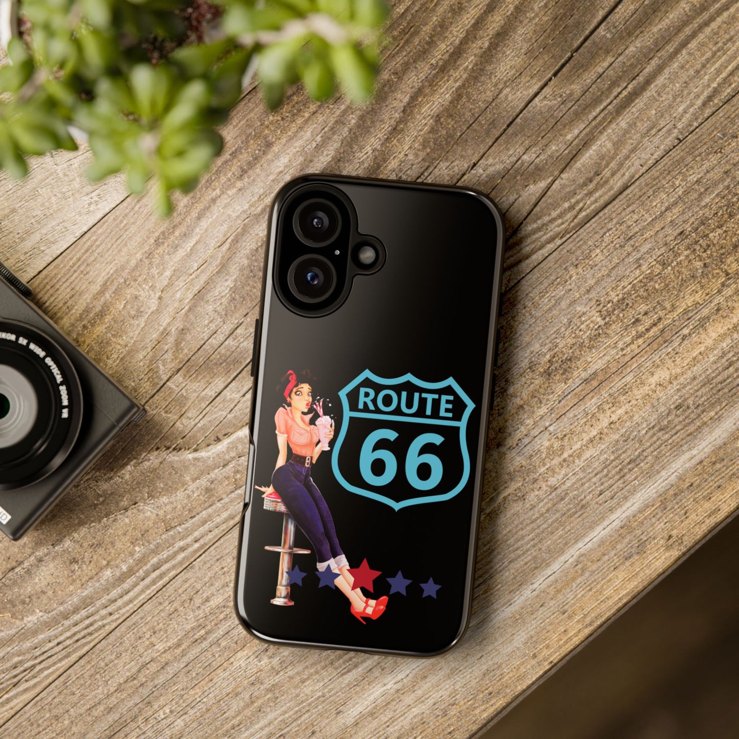 Route 66 Milkshake Girl iPhone case displayed flat on wooden desk with camera nearby, highlighting retro diner design and glossy finish