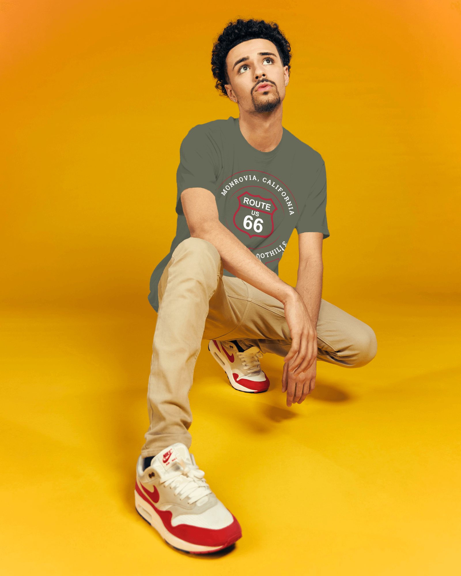 Male model wearing heather military green retro Route 66 unisex jersey tee with Monrovia, CA: "Gem of the Foothills" design