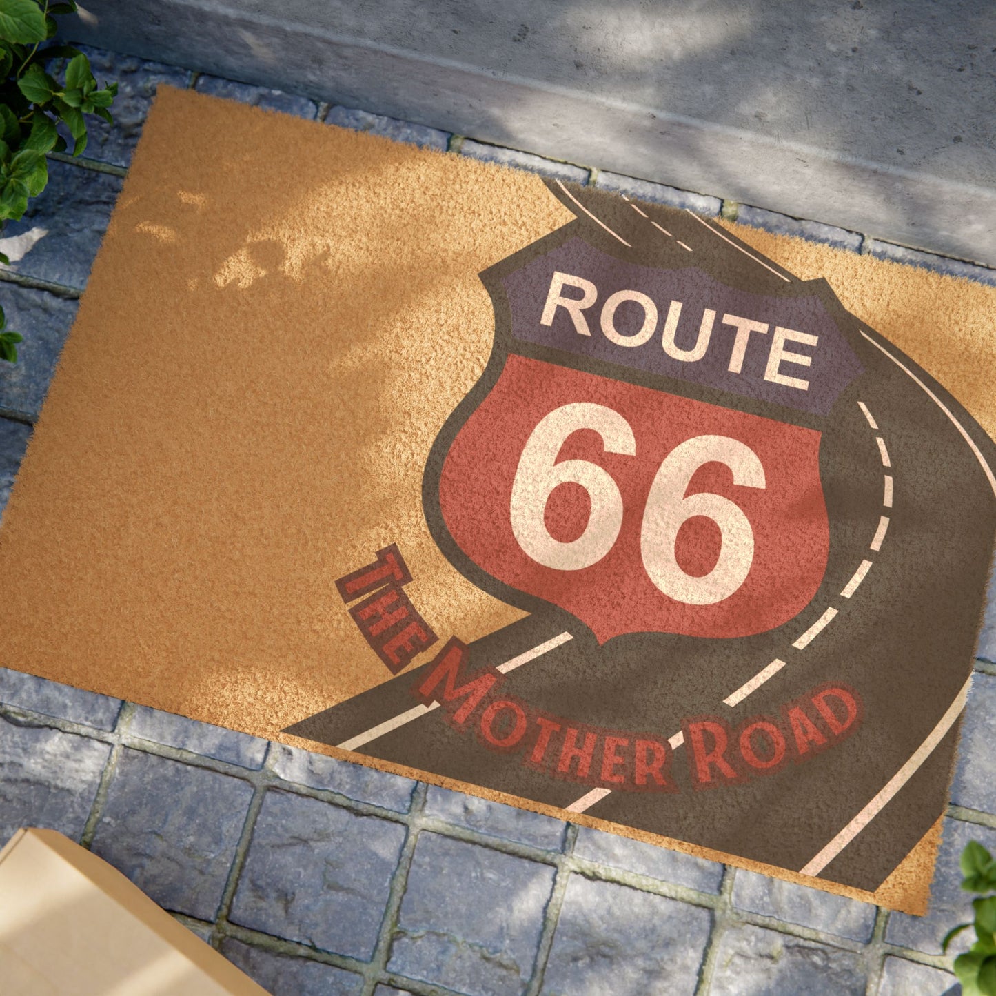 Styled photo of Route 66 'The Mother Road' doormat on a rustic wooden porch with plaid rug, creating a warm and welcoming entryway scene