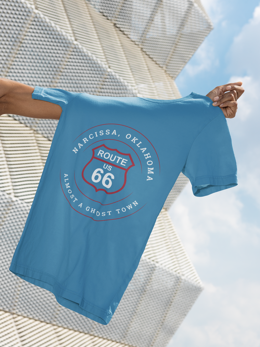 Aqua retro Route 66 unisex jersey tee with Narcissa, OK "Almost a Ghost Town"  design being held by the arm of a hidden person