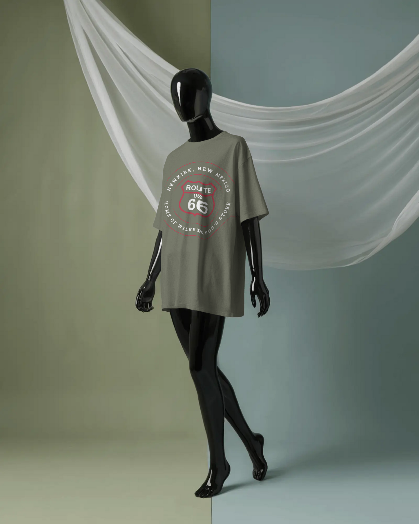 Mannequin model wearing heather military green retro Route 66 unisex jersey tee with Newkirk, NM: "Home of Wilkerson's Store" design