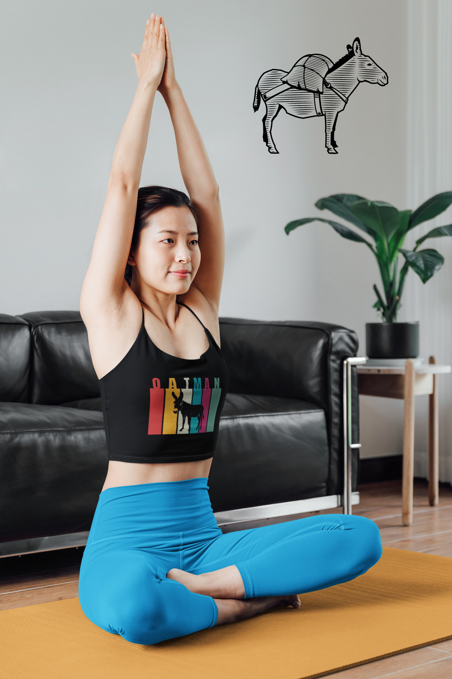 Woman wearing Oatman Arizona Route 66 Burro Tank Top while doing yoga at home. Its soft and stylish festival crop top inspired by dessert road trip fashion intersecting with donkeys.
