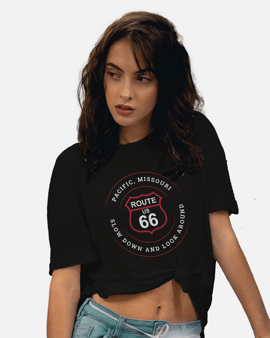 Female model wearing a black heather retro Route 66 unisex jersey tee with a Pacific, MO: "Slow Down And Look Around" design