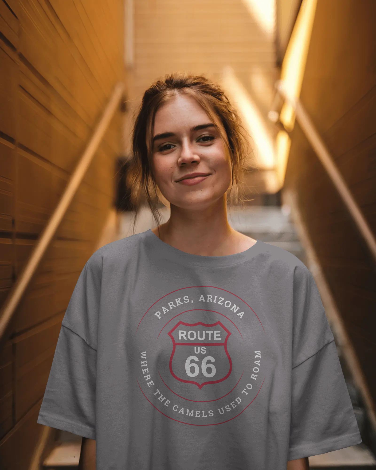 Female model wearing dark grey heather retro Route 66 unisex jersey tee with Parks, AZ: "Where the Camels Used to Roam" design