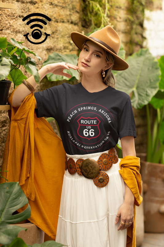 Female model wearing a fedora, a black retro Route 66 unisex jersey tee with Peach Springs, AZ: "Hualapai Reservation on 66" design and a western belt.