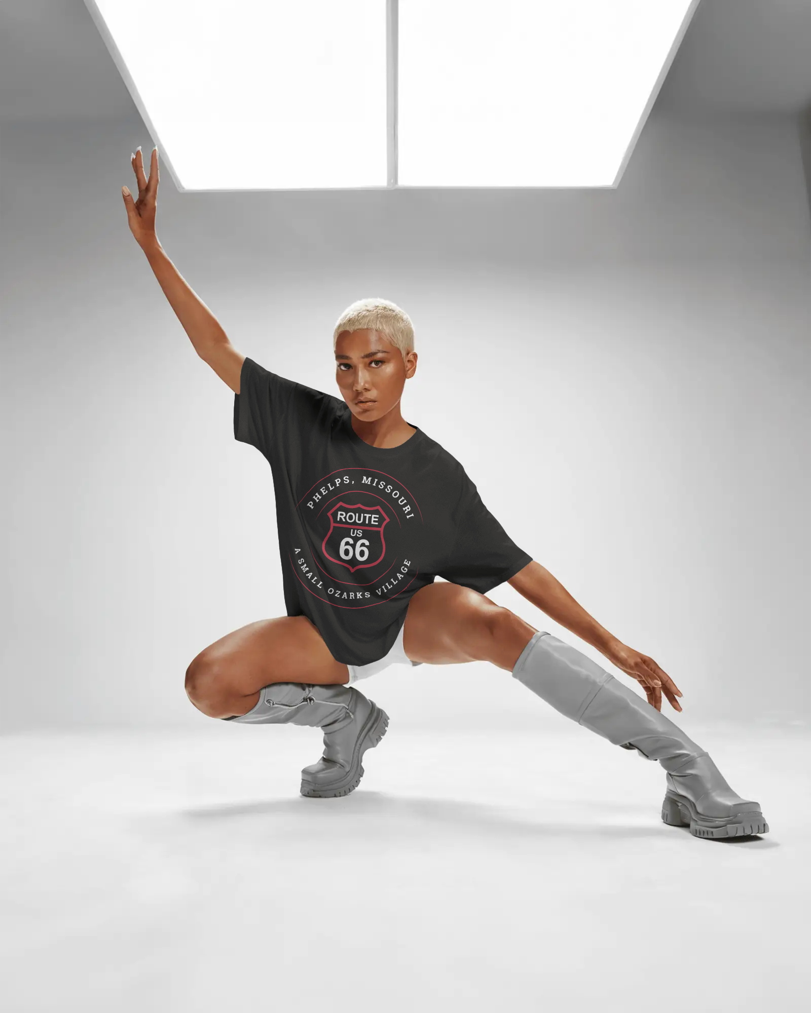 Female model doing a yoga pose and wearing a vintage black retro Route 66 unisex jersey tee with Phelps, MO "A Small Ozarks Village" design