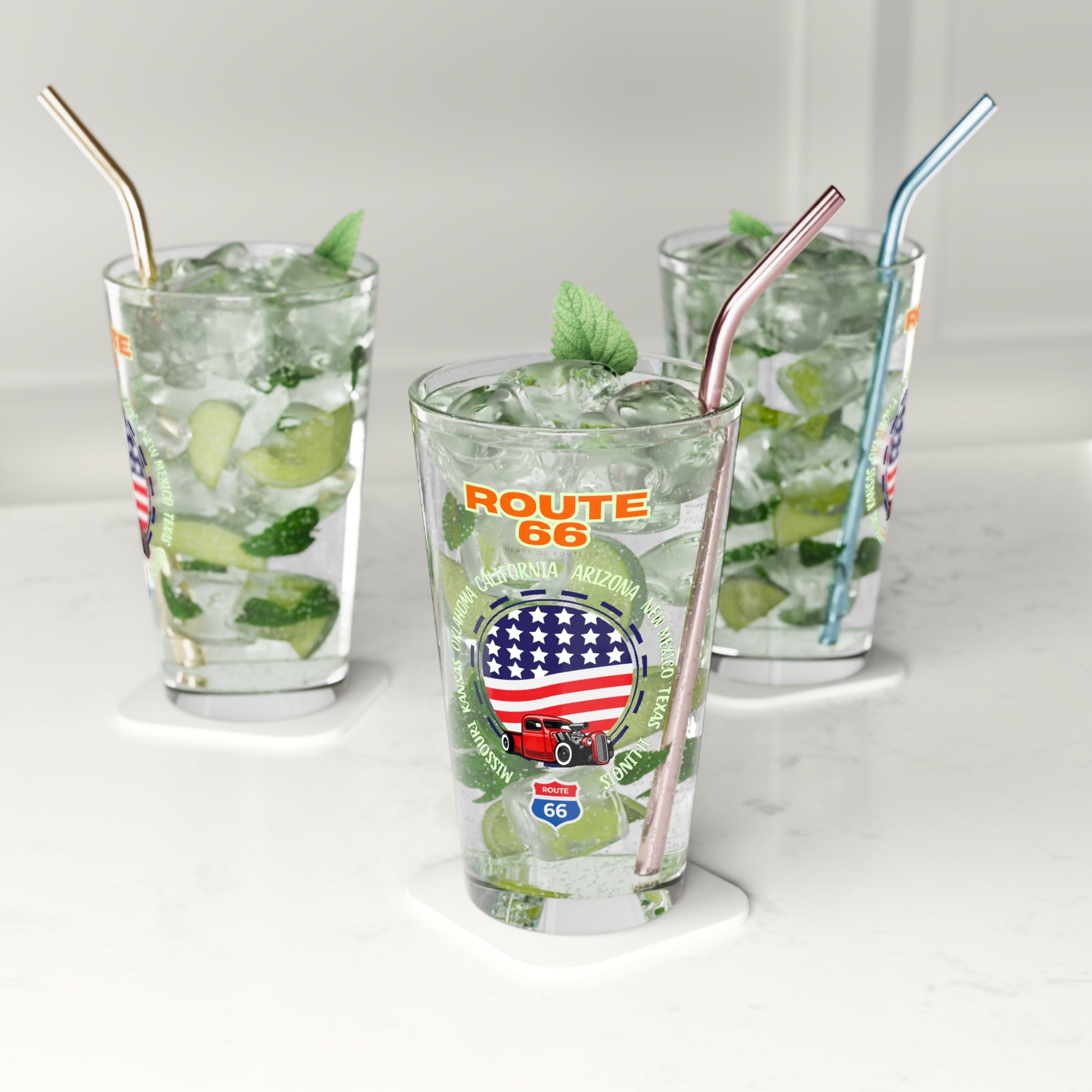 Set of Route 66 pint glasses filled with mojitos and reusable metal straws on a white counter, showcasing the vintage Americana truck and flag design