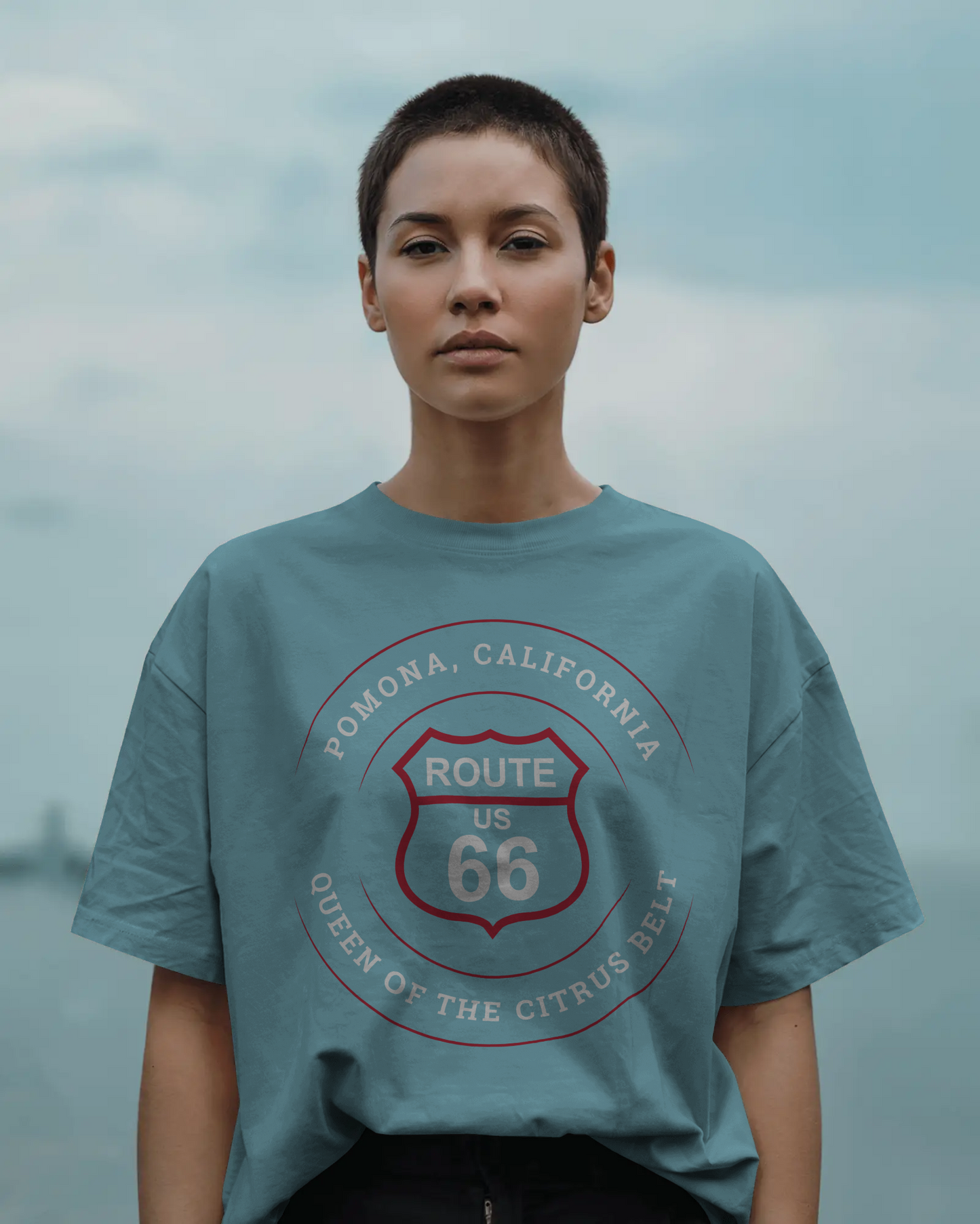 Female model wearing turquoise retro Route 66 unisex jersey tee with Pomona, CA: "Queen of the Citrus Belt" design