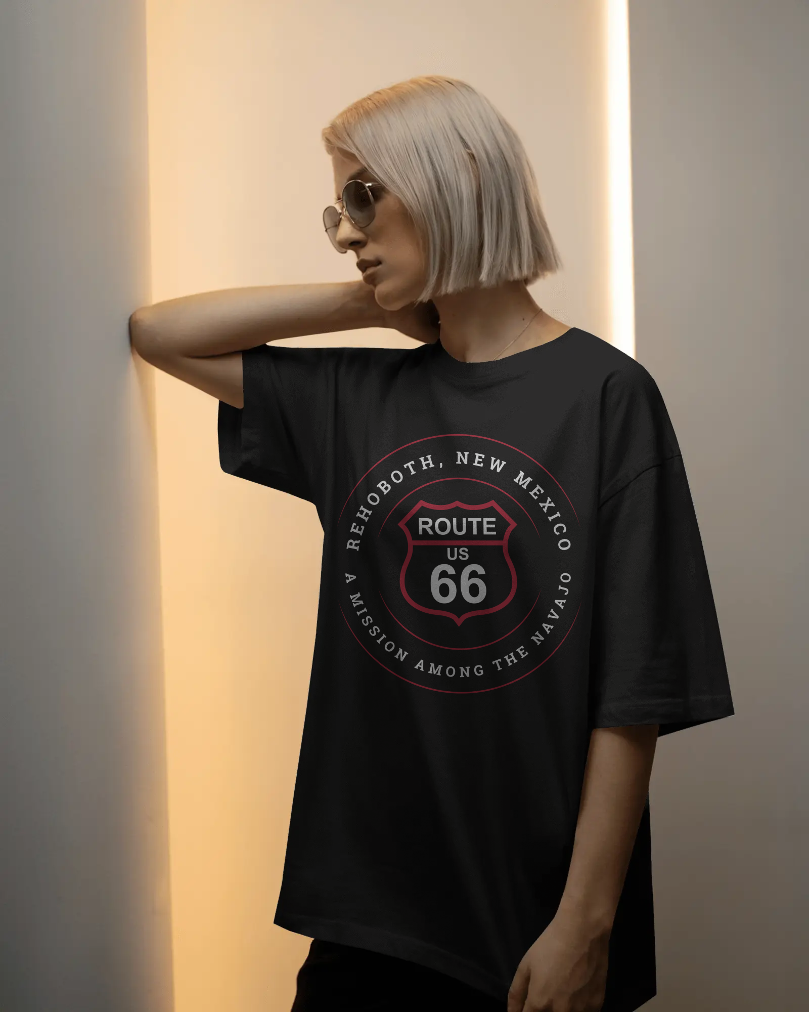 Female model wearing vintage black retro Route 66 unisex jersey tee with Rehoboth, NM: "A Mission Among the Navajo" design
