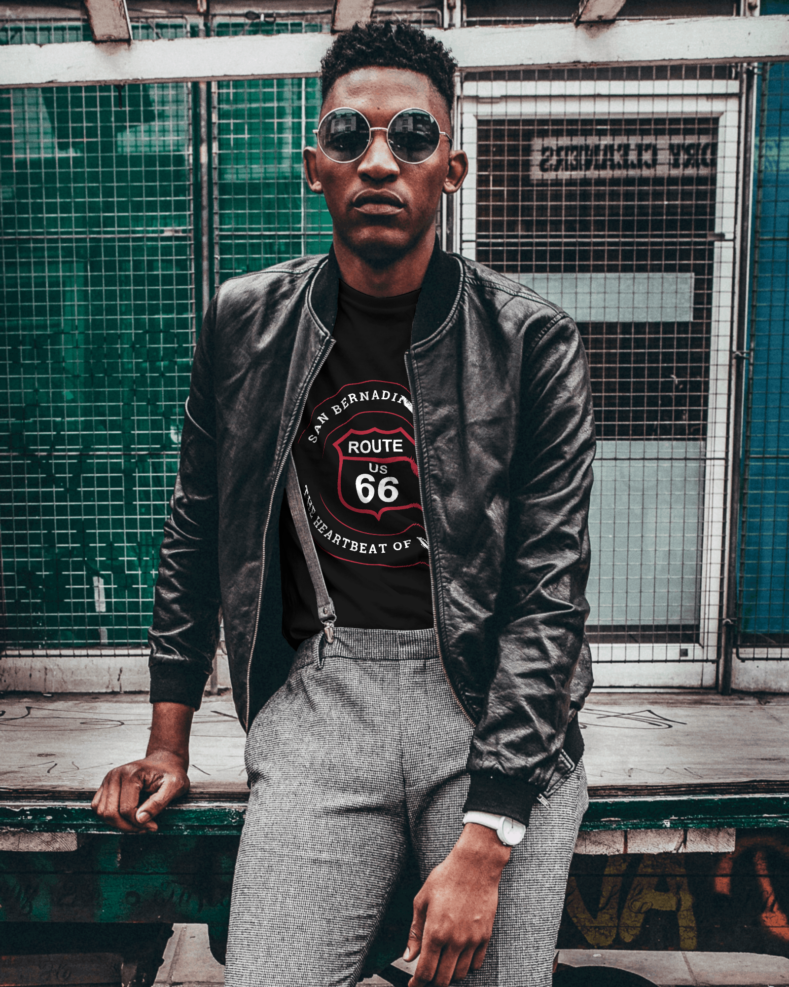 Male model wearing black leather jacket and black retro Route 66 unisex jersey tee with San Bernardino, CA: "Heartbeat of Route 66" design