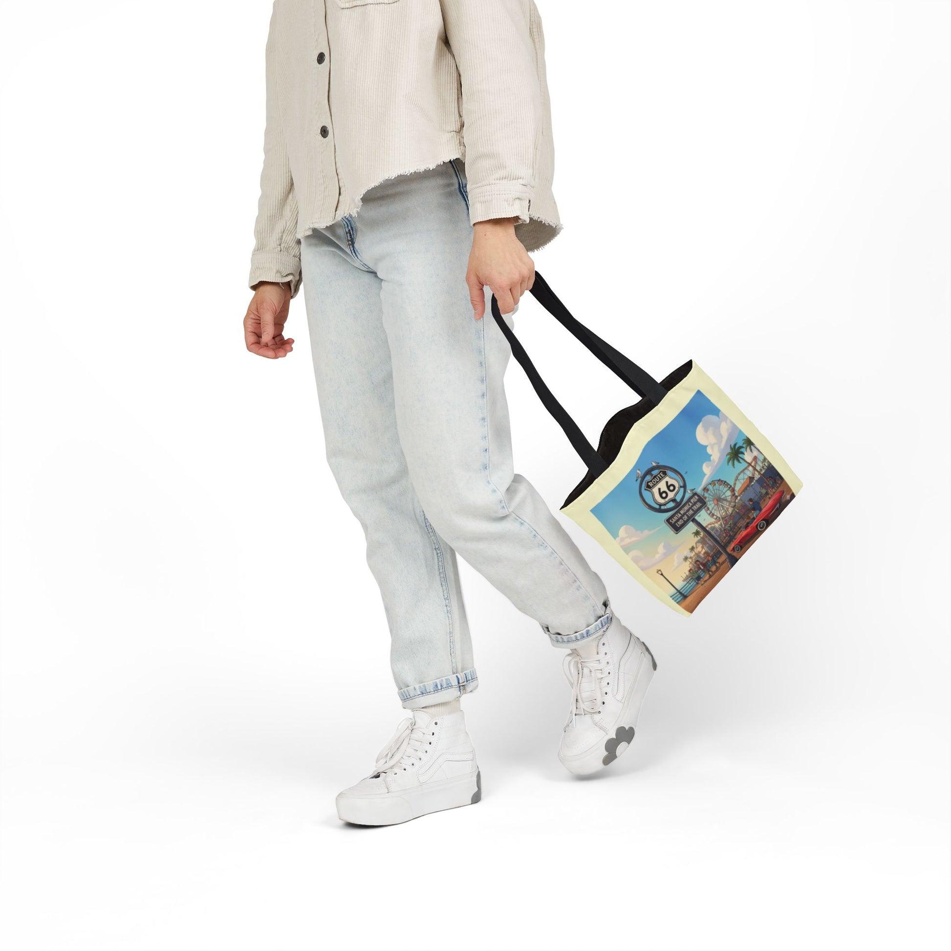 Lifestyle view of Route 66 Santa Monica Pier End of the Trail tote bag with black handle is being carried by a person, showcasing beach and pier artwork design