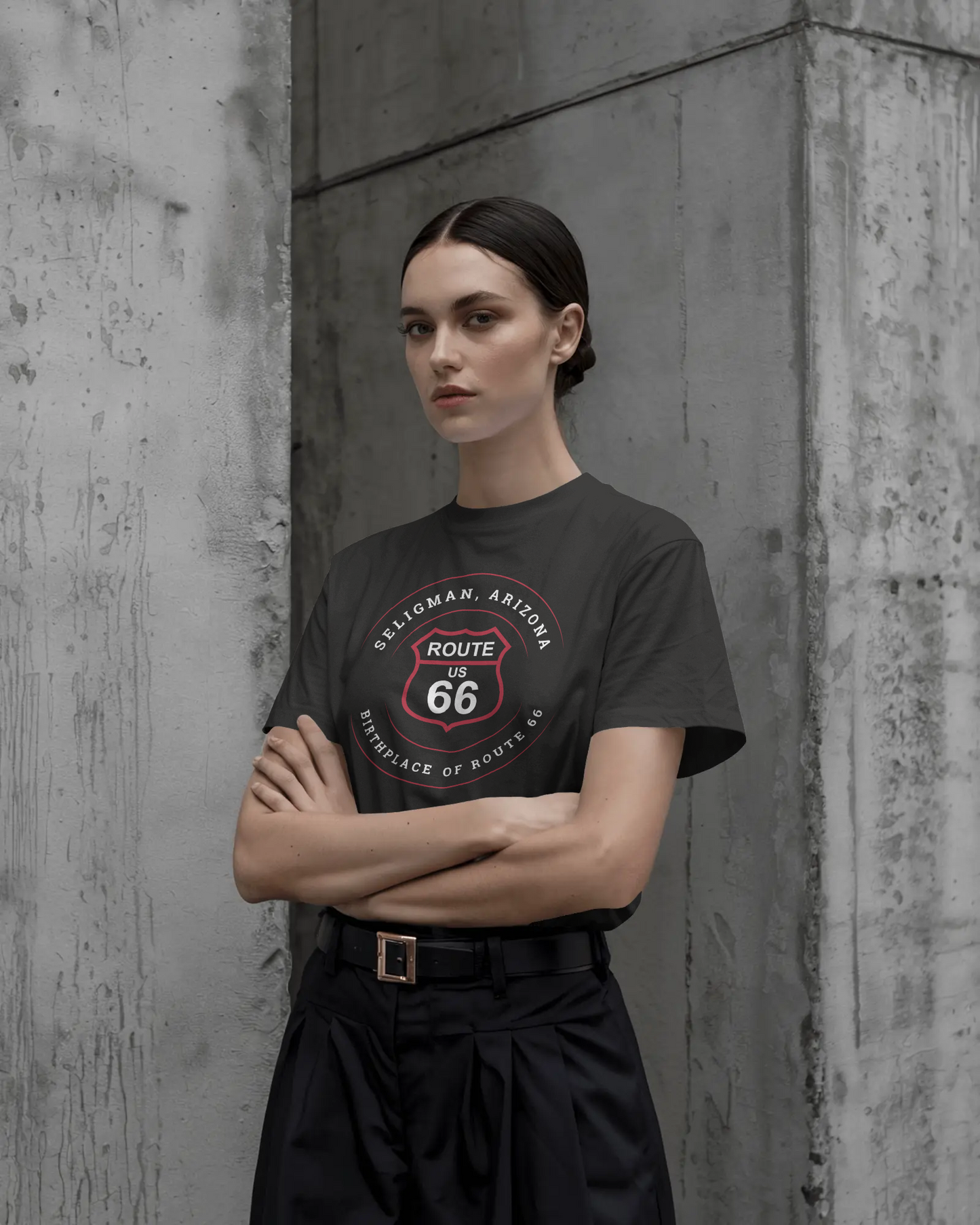 Female model with arms crossed and is wearing a black retro Route 66 unisex jersey tee with Seligman, AZ: "Birthplace of Route 66" design