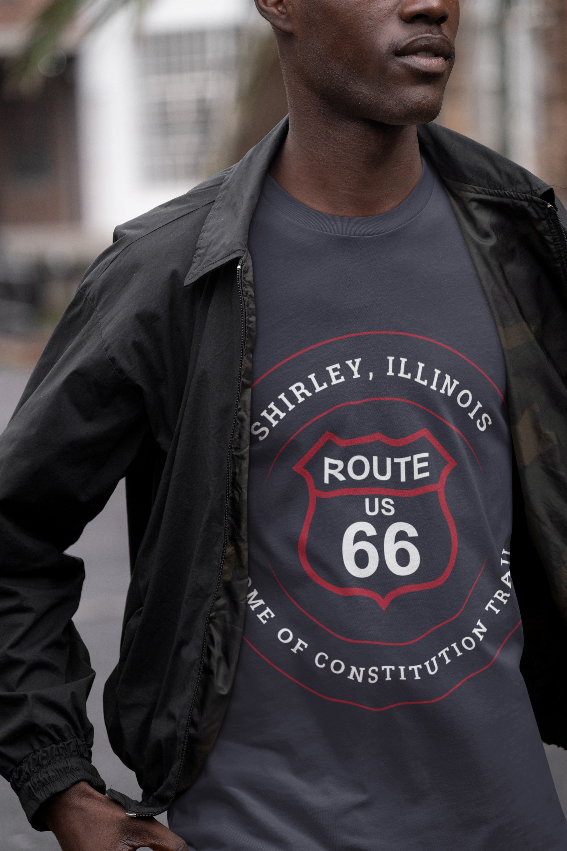 Male model wearing a vintage black retro Route 66 unisex jersey tee with a Shirley, IL: "Home of the Constitution Trail" design
