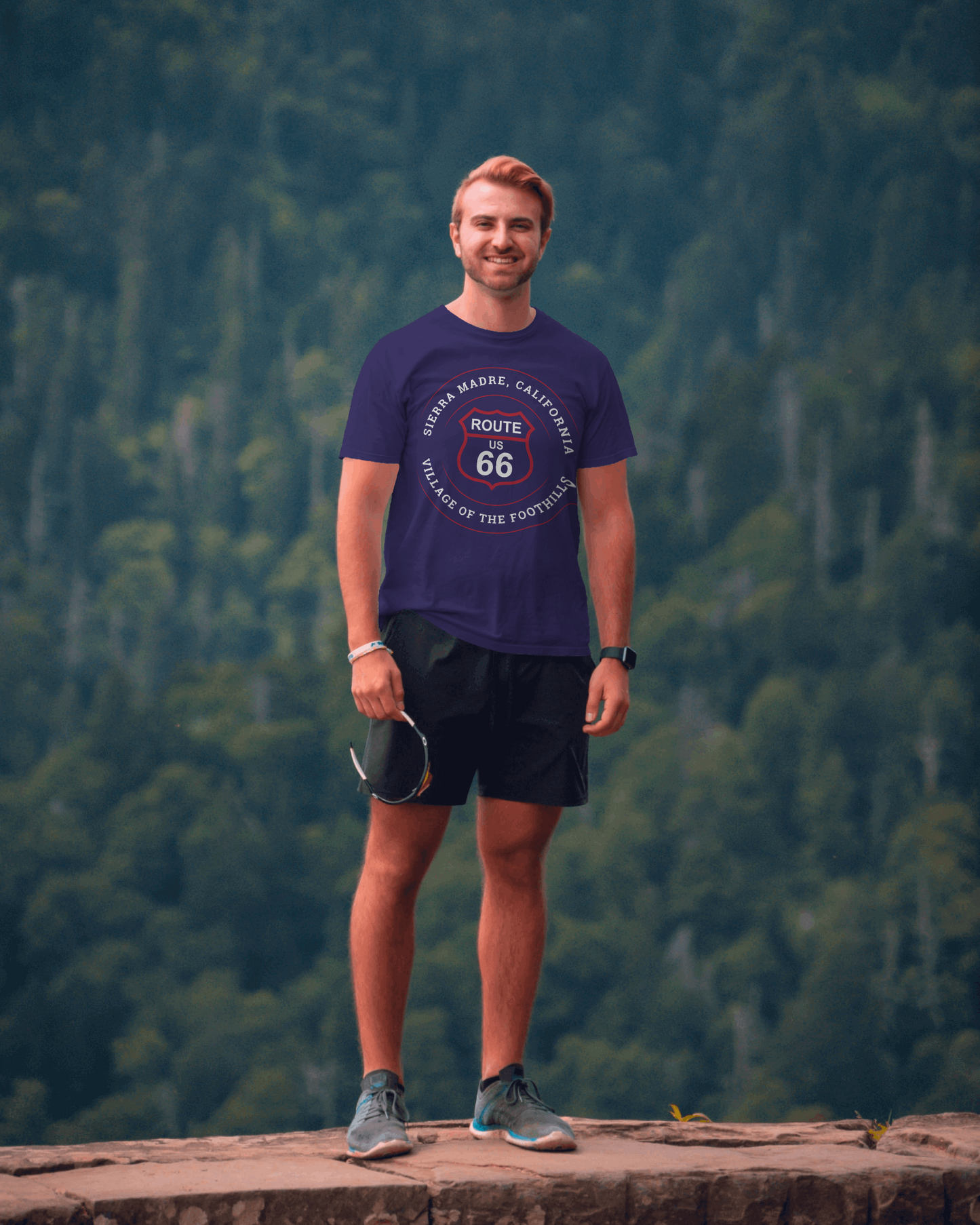 Male model in the San Gabriel Mountains wearing team navy retro Route 66 unisex jersey tee with Sierra Madre, CA: "Village of the Foothills" design