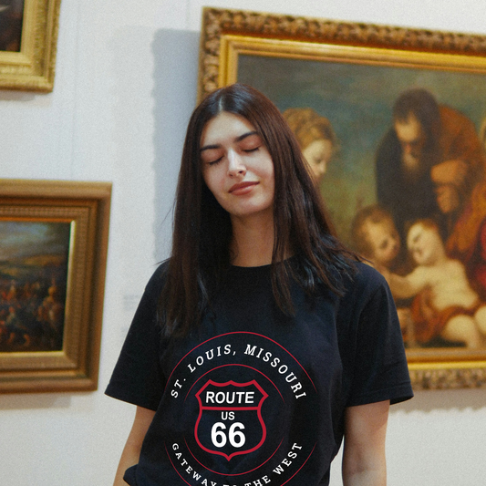 Female model wearing a black heather retro Route 66 unisex jersey tee with a St. Louis, MO: "Gateway to the West" design