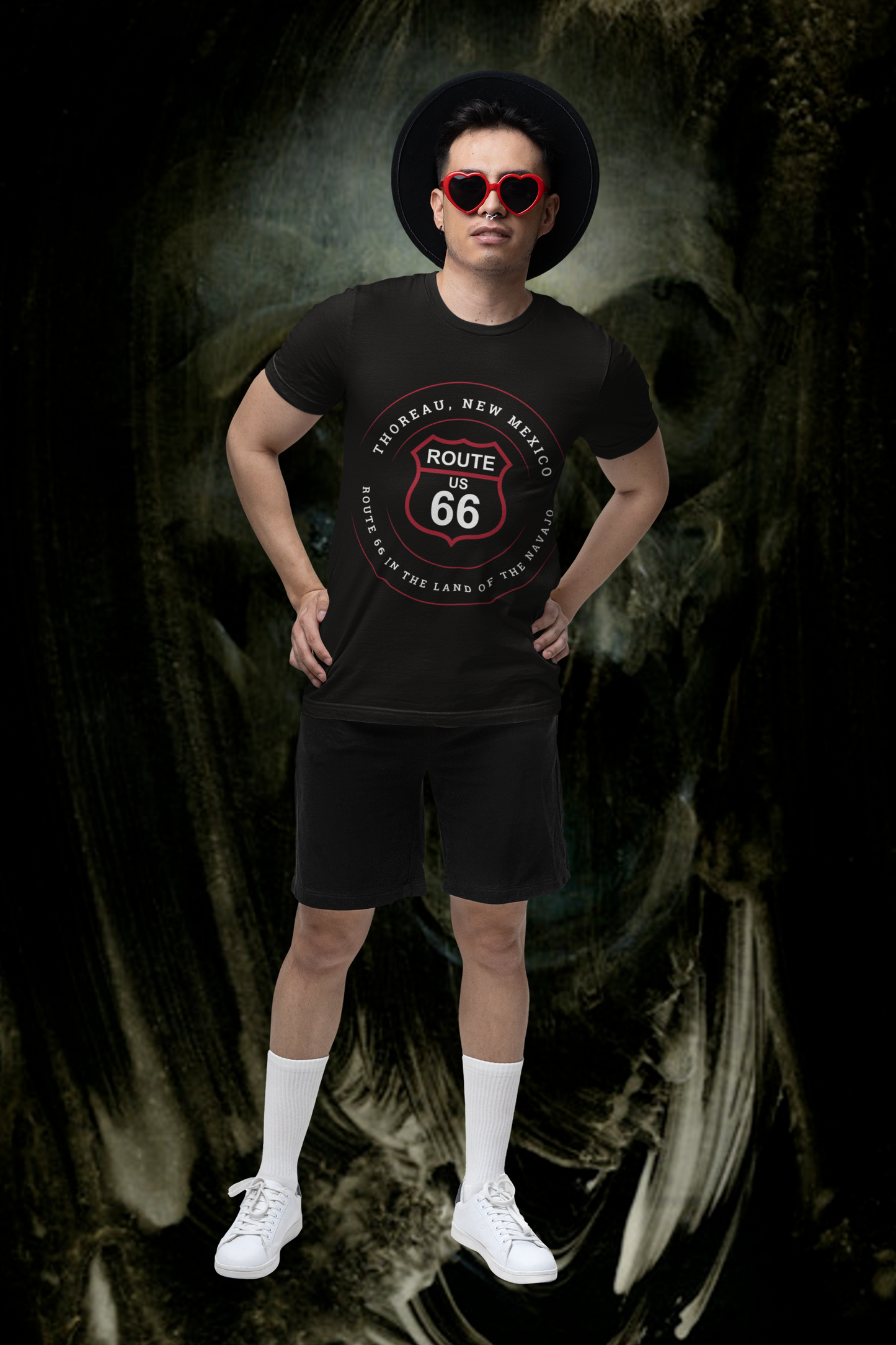 Female model wearing heart-shaped red sunglasses and a black retro Route 66 unisex jersey tee with Thoreau, NM: "Route 66 in the Land of the Navajo" design
