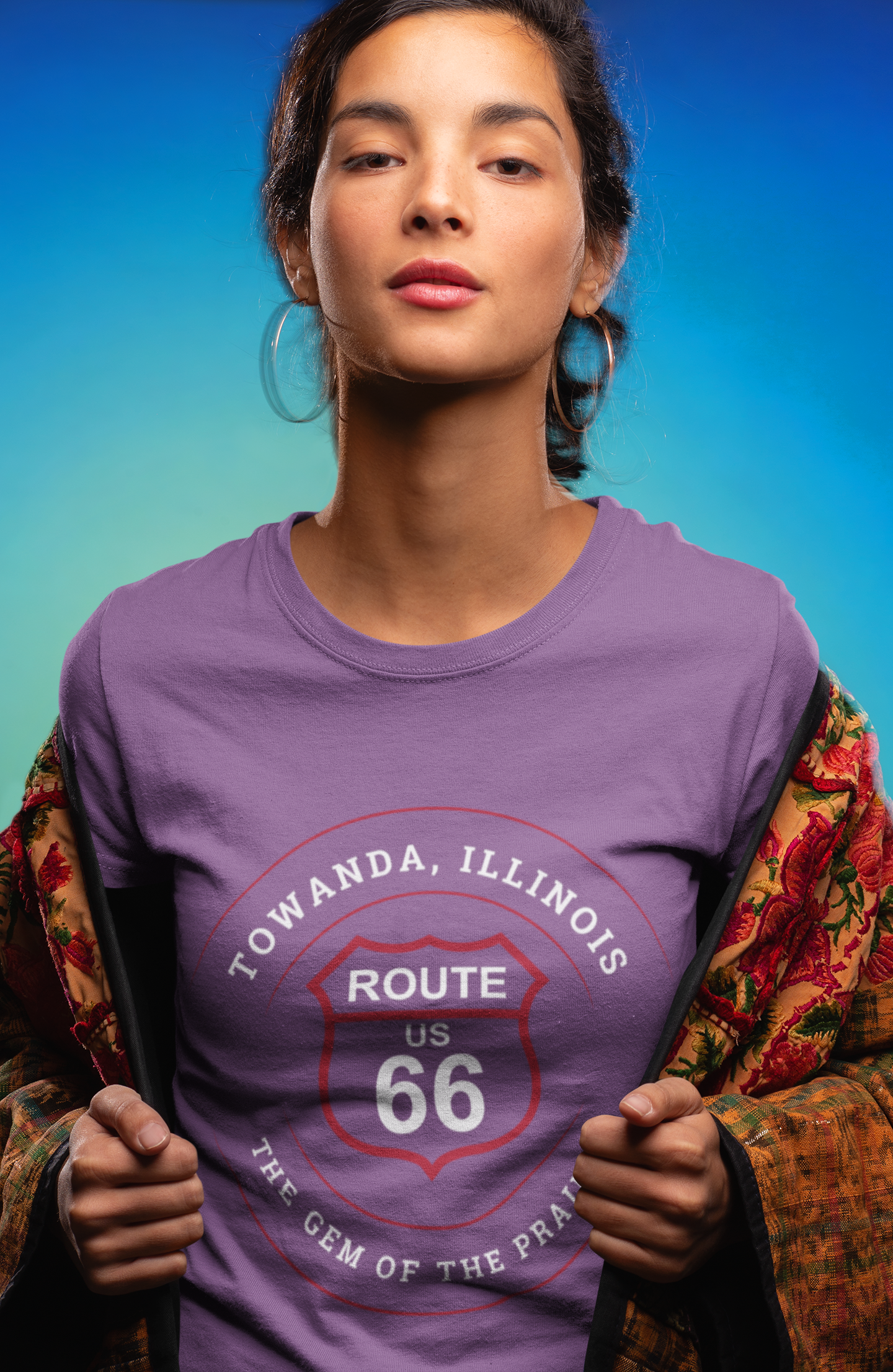 Female model wearing a heather team purple retro Route 66 unisex jersey tee with a Towanda, IL: "Gem of the Prairie" design